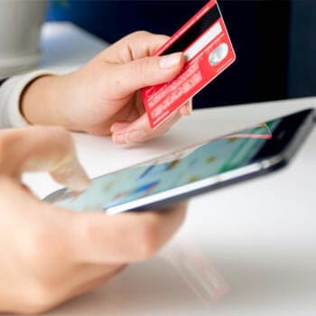 Hand view of a person using his phone while holding a credit card