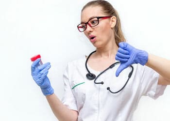 A female doctor holding up a urine sample and a thumbs down