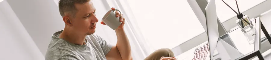 A person drinking coffee while looking at a laptop
