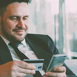 A person holding a credit card and phone